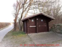 Toilette am Strandaufgang 2 - Toilettenhaus mit Bäumen im Hintergrund